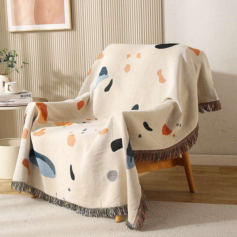 Modern shell-pattern throw blanket draped over a wooden chair in a cozy living room