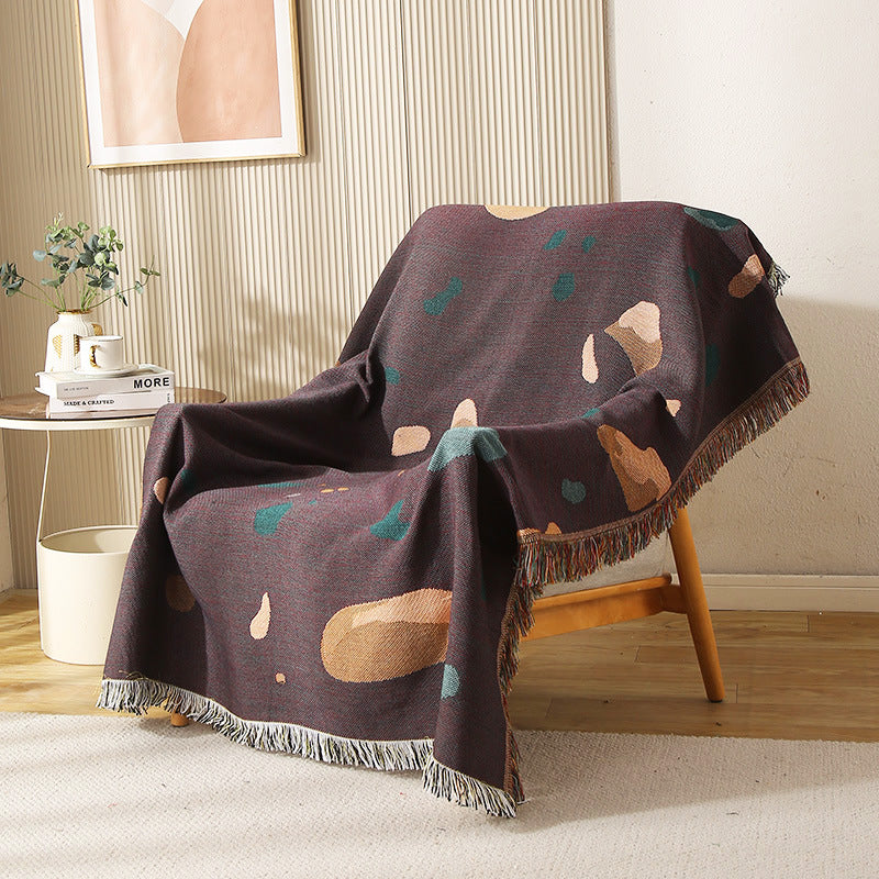 Modern shell-pattern throw blanket draped over a wooden chair in cozy living room