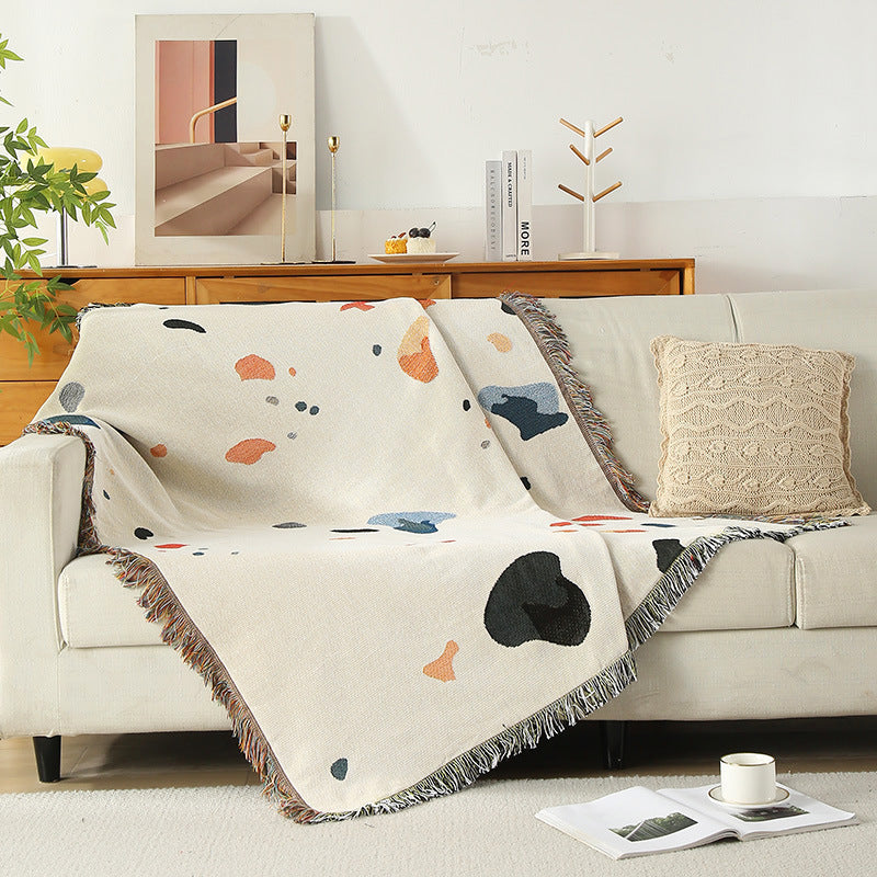 Modern shell-pattern throw blanket used as sofa cover in minimalist interior