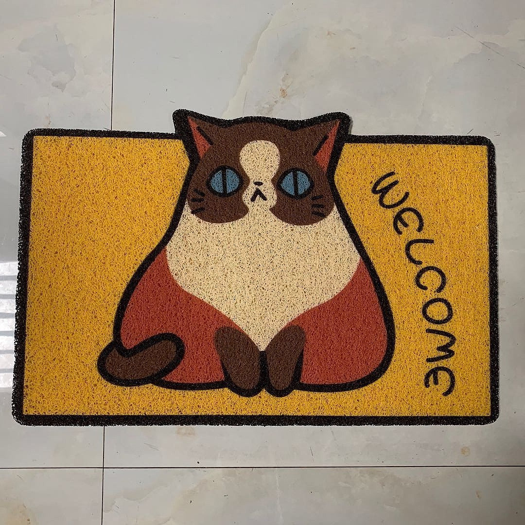 Doormat with a cartoon cat design and 'Welcome' text on a tiled floor.